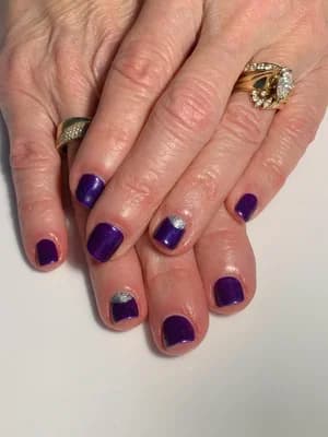 Short nails in dark purple polish with two silver glitter accent nails.