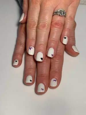 Short white nails accented with small black and purple heart outlines.