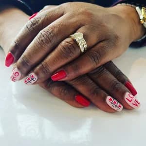 Glossy red nails with white accents lettered in red spelling LOVE.