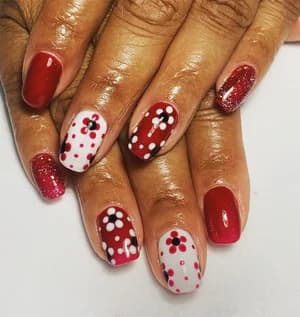 Red and white nails with black and pink polka dot daisy flowers.
