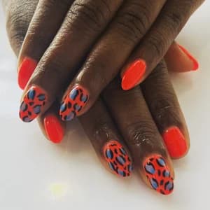 Almond nails in bright orange-red with blue and black leopard print accents.