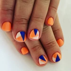 Short nails mixing solid orange with color-blocked geometric triangles in blue, orange, and white.