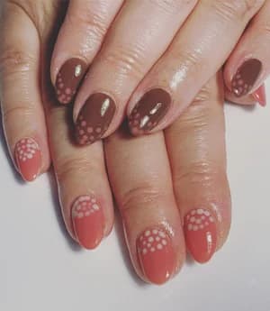 Short brown and terracotta nails with white dotted half-flower burst designs.