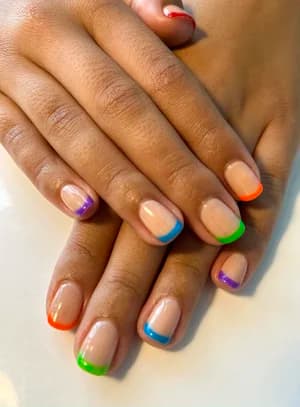 Natural nude nails with multicolored French tips in orange, green, blue, purple and red.