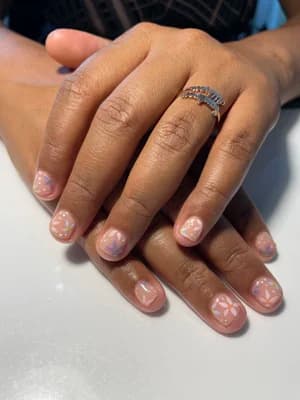 Short nude pink nails with subtle iridescent opal marble accents scattered across the surface.