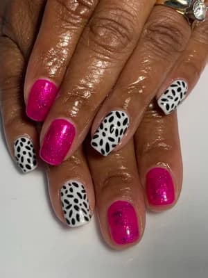 Magenta glitter nails alternating with white nails covered in black dalmatian spots.