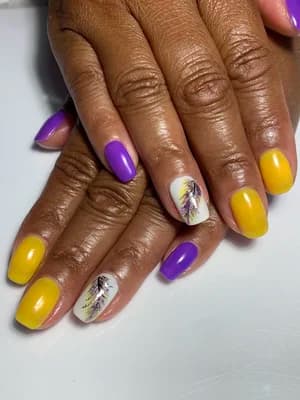 Alternating purple and yellow solid nails with white feather design accent nails.