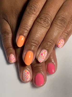 Solid orange and pink nails with white confetti dot floral accent nails.