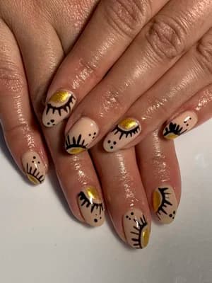 Nude nails with black eyelash and dot designs plus gold metallic half-moon accents.
