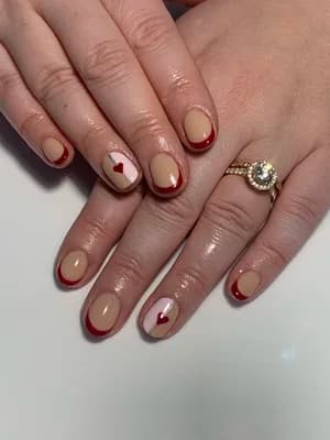 Nude nails with dark red French tips and a small red heart accent.