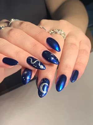 Metallic navy blue almond nails with celestial moon, stars, and white swirl designs.