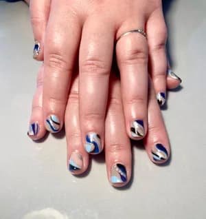 Abstract marble swirls in navy, light blue, and white across short nails.