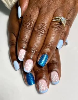 Light blue and white nails with white snowflakes and navy glitter accent nails.