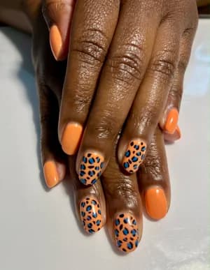 Solid orange nails with leopard print accents in blue and black spots.