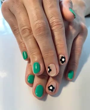 Green solid nails paired with nude accents featuring black-and-white daisy flower details.