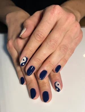 Navy blue nails with white yin-yang swirl accents on two fingers.