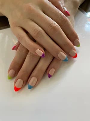 Nude almond nails with multicolored rainbow French tips, each tip a different color.