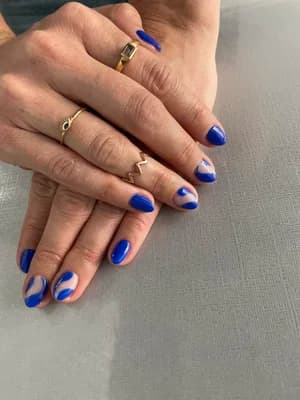 Cobalt blue nails with abstract swirl design revealing nude base underneath.