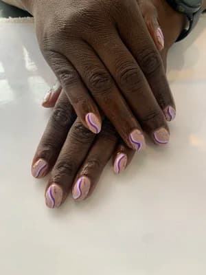 Short rounded nails with sheer nude base and lavender-and-white swirling wave lines across each nail.