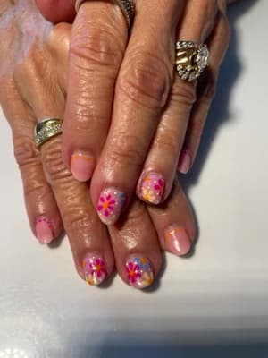 Short nails with sheer base and hand-painted daisy flowers in pink, orange, and yellow.
