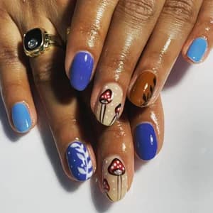 Blue and orange nails with hand-painted red toadstool mushrooms and delicate floral line work