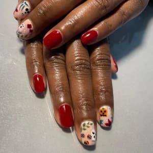 Glossy red nails with autumn accent art: pumpkins, ghosts, and scattered fall leaves