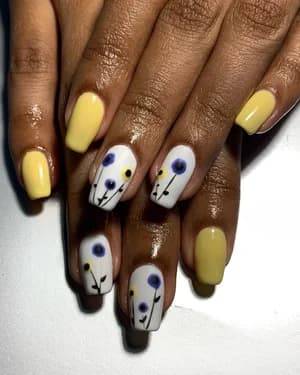 Alternating pastel yellow and white nails with blue and purple wildflower line art