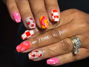 Squared nails mixing pink, orange and white with wavy swirls, checkerboard, and red berry dots
