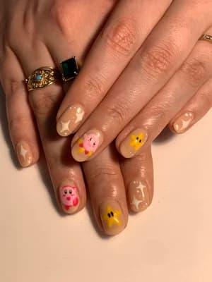 Beige base nails featuring pink Kirby character art plus yellow and white star accents