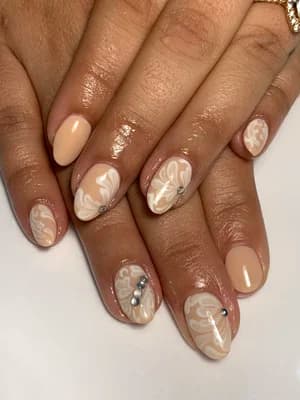 Nude almond nails with cream white marble swirl accents and silver rhinestone gem clusters