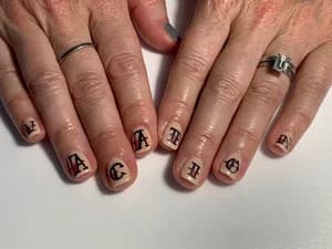 Short beige nails each painted with a single black gothic blackletter capital letter