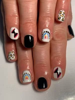 Black and white nails featuring rainbows, lightning bolts, and leopard print accent designs