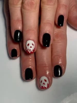Glossy black nails with white accent nails showing red-dripping skull designs, Halloween theme