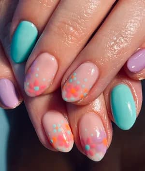 Pastel almond nails in lilac, mint, and nude scattered with orange, teal, and pink polka dots