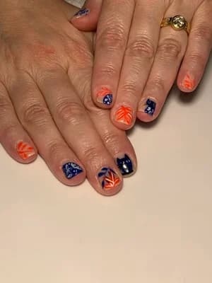 Short nails in navy and burnt orange with fall leaves and black cat silhouettes on nude bases