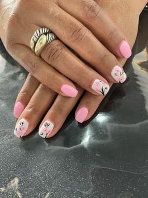 Soft pink and white nails with delicate black line-work floral stems and tiny buds