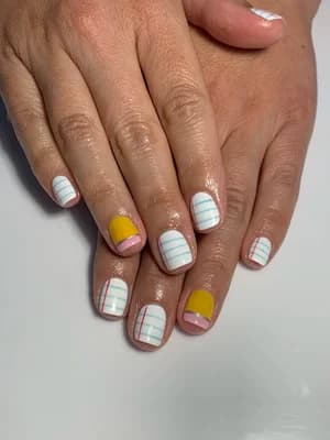 White nails with pastel plaid stripe line work and two solid mustard yellow accent nails