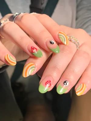 Sage green almond nails with retro rainbows, yin-yang symbols and red spotted mushrooms