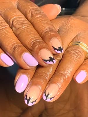 Lilac purple nails with black bat silhouette tips, negative-space French line work.
