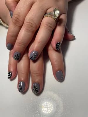 Gray short nails with black hand-painted leaf and branch botanical line work.